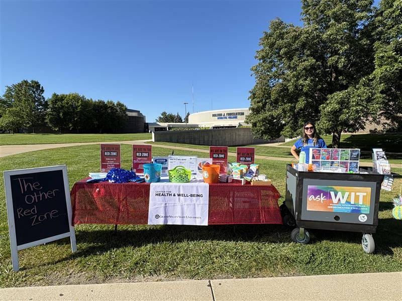image of table and WIT peer educator at GVSU tailgating